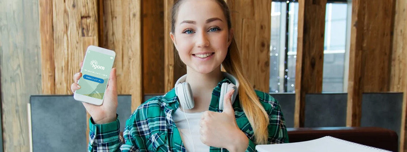 Een vrouw met headphones steekt haar duim op en laat de IGOM website zien op haar telefoon