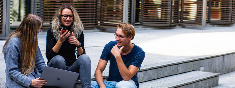 Drie mensen die buiten op een trapje zitten en overleggen